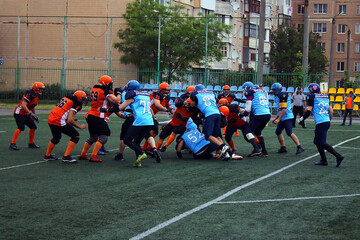 Many American football players fight for the ball on the green stadium