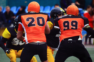 Two American football players in black and orange uniforms with numbers 20 and 99 on their backs