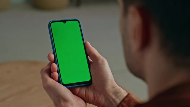Man hands holding mockup smartphone at home close up. Guy with chroma key mobile