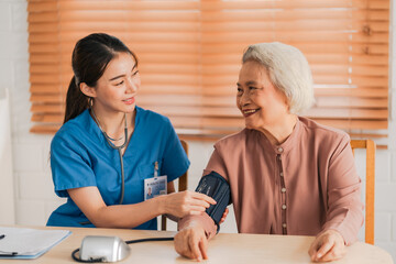 Medical health insurance service, Asian caregiver doctor examine older patient use blood pressure gauge. Young woman therapist nurse nursing home taking care to senior elderly woman