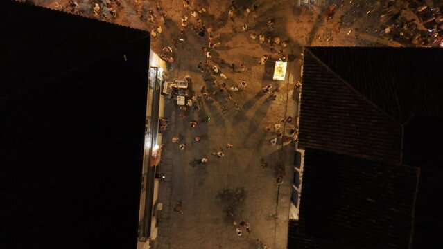 Aerial shot drone with camera pointing down as drone flies backwards and pans up at night in historic downtown