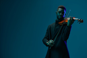 Elegant man playing violin in a suit on dark blue background for classical music concept