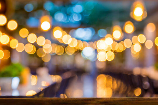 Blurred restaurant or cafe background. Tables and chairs in the lobby of restaurant. Visitors to restaurant for dinner. Cozy bokeh lightening. Beautiful bright interior. Blurred bokeh basic background