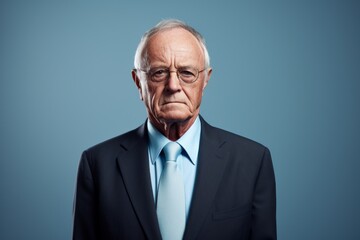 Portrait of senior businessman in suit and eyeglasses on blue background