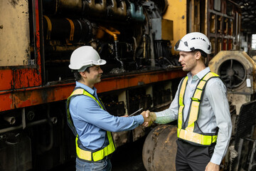 Team railway engineer Inspect repair project train diesel engine in maintenance center shake hand. Technician discuss planning checking vehicle and railroad systems.