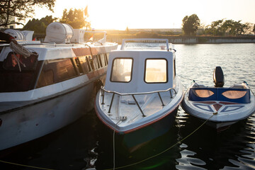 three boats docked in a harbor at sunset.