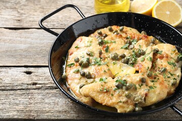Delicious chicken piccata with herbs on wooden table. Space for text
