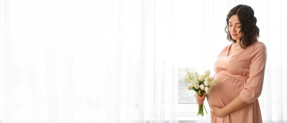 Young pregnant woman with tulips near window at home. Banner for design