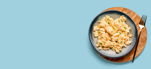 Scrambled eggs on plate against light blue background with space for text