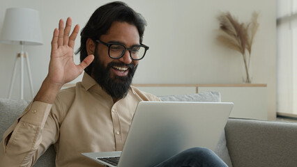 Arabian Indian muslim man talk at home video call conference on laptop freelance businessman speak...