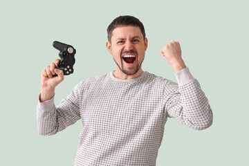 Happy young man with game pad on green background