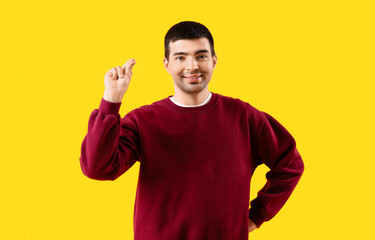 Young man snapping fingers on yellow background