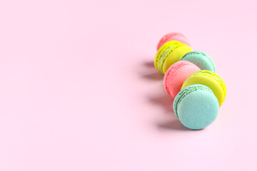 Different tasty sweet macaroons on pink background