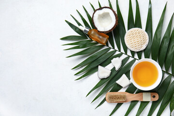 Bottle and bowl of coconut cosmetic oil with massage brushes on white background