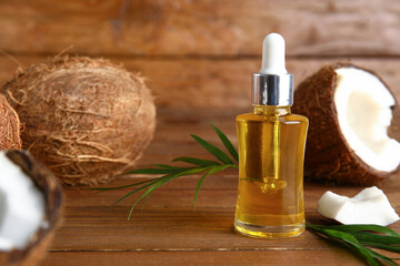 Bottle of coconut cosmetic oil with plant leaves on brown wooden background