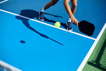 A man in a hat plays pickleball on a blue court