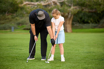 A father and Daughter play golf on a golf course