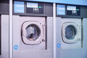 Inside a laundromat establishment. High load automatic industrial washing machines.