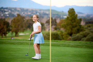 A young girl celebrates a putt on a putting green