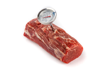 A beef tenderloin center cut roast with an analog meat thermometer isolated on whit