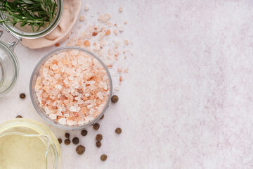 Glass bowl of Himalayan pink salt with peppercorn and rosemary on white background
