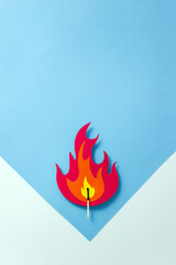 Paper cut flame and match on blue and white background. The concept of careful handling of fire. Copy space, selective focus