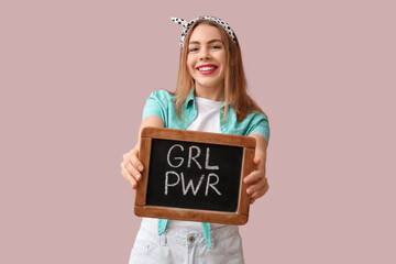 Happy young pin-up woman holding chalkboard with text GIRL POWER on pink background