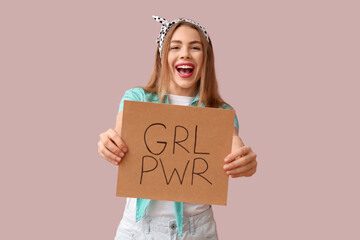 Happy young pin-up woman holding card with text GIRL POWER on pink background