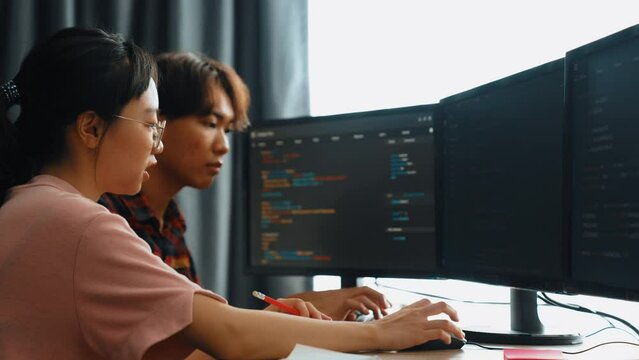 Slow motion back end software developer engineer for computer programming working together on debugging writing computing code, solving complex algorithms display on monitor in office. Burgeoning