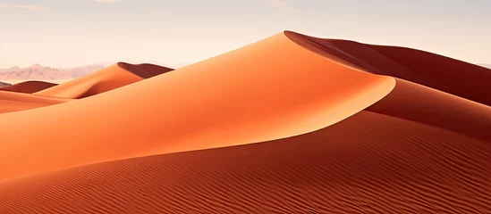 Selbstklebende Fototapeten A group of red sand dunes dominates the foreground, with towering mountains in the background. Barchan dunes create a mesmerizing landscape as they traverse the desert terrain. © AkuAku