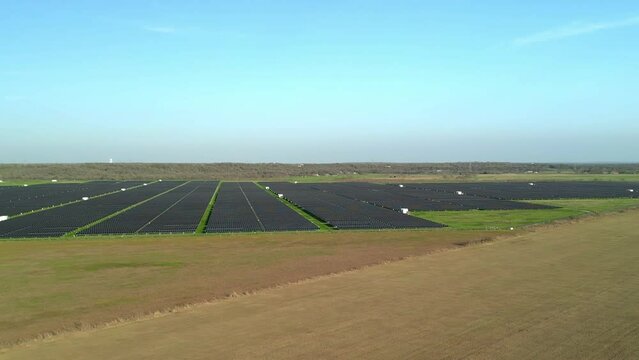 Panning aerial view of solar farm in rural field outside major city