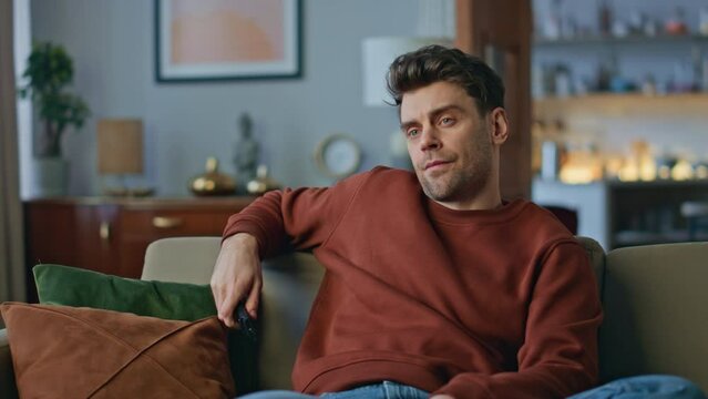 Bored hipster choosing movie chilling at couch close up. Man switching channels