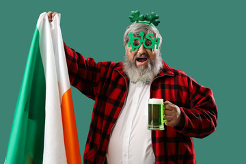 Mature man with Irish flag and beer on green background. St. Patrick's Day celebration