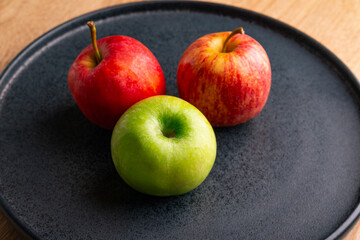 delicious and healthy apples on a pallet on a wooden table, bitten apple, red apple and green apple