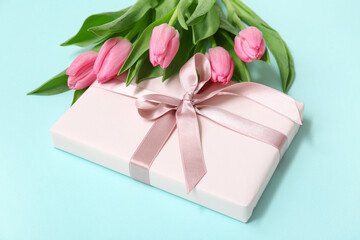Gift box and bouquet of beautiful tulips on blue background. International Women's Day