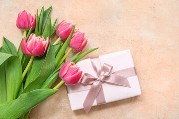 Gift box and bouquet of beautiful tulips on beige background. International Women's Day