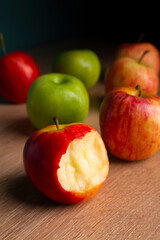 delicious apples on a wooden table, bitten apple, red apple and green apple