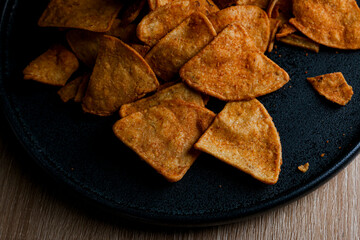 nachos with barbaco on a dark plate on a wooden table, delicious snack of nachos with cheese