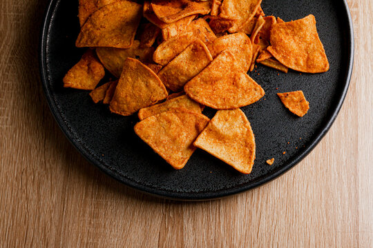 nachos with barbaco on a dark plate on a wooden table, delicious snack of nachos with cheese