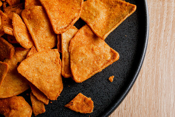 nachos with barbaco on a dark plate on a wooden table, delicious snack of nachos with cheese