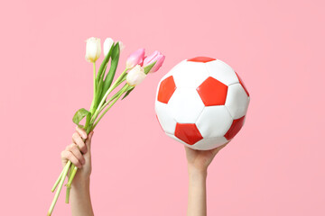 Female hands with soccer ball and tulip flowers for International Women's Day on pink background,...