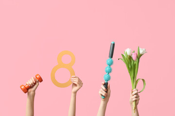 Female hands with paper figure 8, sports equipment and tulip flowers for International Women's Day on pink background