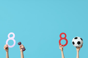 Female hands with paper figures 8, dumbbell and soccer ball on color background. International Women's Day
