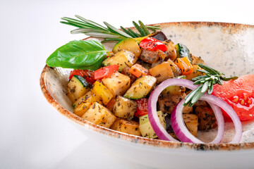 Vegetable Ratatouille with tomatoes, zucchini, pepper and seasonings in a plate on a white background. A traditional French vegetable dish cooked in the oven, top view
