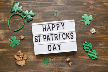 Board with words HAPPY ST PATRICKS DAY, plastic eyeglases and decor on wooden background