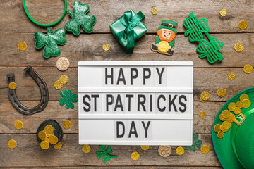 Board with words HAPPY ST PATRICKS DAY, leprechaun hat and decor on wooden background