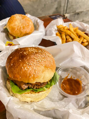Close-up photo of Burgers wrapped with white food paper. French fries and ketchup sauces. Concept for junk food, unhealthy, diet, calories, bad fat.