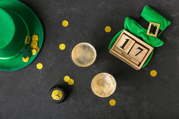 Glasses of dark beer with leprechaun hats, pot of golden coins and calendar for St. Patrick's Day...