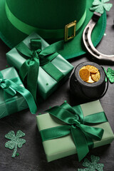 Leprechaun hat with pot of golden coins, gift boxes and horseshoe on black grunge background. St. Patrick's Day