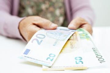 Retired elderly woman counting coins money and worry about monthly expenses and treatment fee payment.